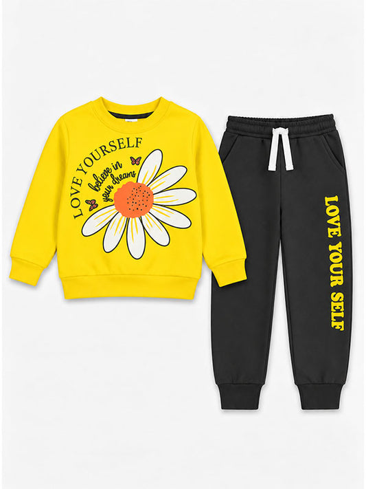 Girls bright yellow sweatshirt with large white daisy graphic and Love Yourself lettering, paired with black trousers with yellow text